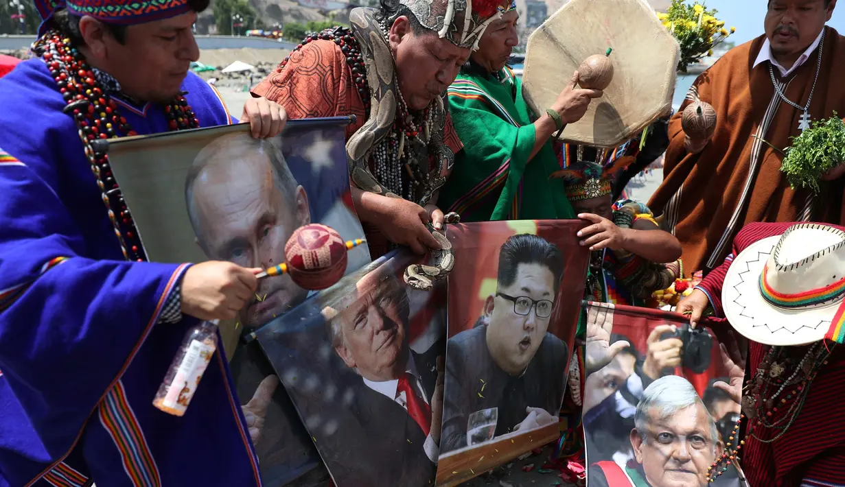 Sekelompok dukun memegang poster Presiden AS Donald Trump, Pemimpin Korut Kim Jong-un, Vladimir Putin dan Presiden Meksiko Andres Manuel Lopez Obrador selama ritual untuk menyambut tahun baru  di pantai Agua Dulce, Lima, Kamis (27/12). (AP/Martin Mejia)
