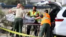 Petugas mengevakuasi jasad korban kecelakaan bus pariwisata di Jalan Raya Southern California, Amerika Serikat, (23/10). Tiga belas orang tewas dan 31 orang lainnya luka-luka dalam kecelakaan maut tersebut. (REUTERS/Sam Mircovich)