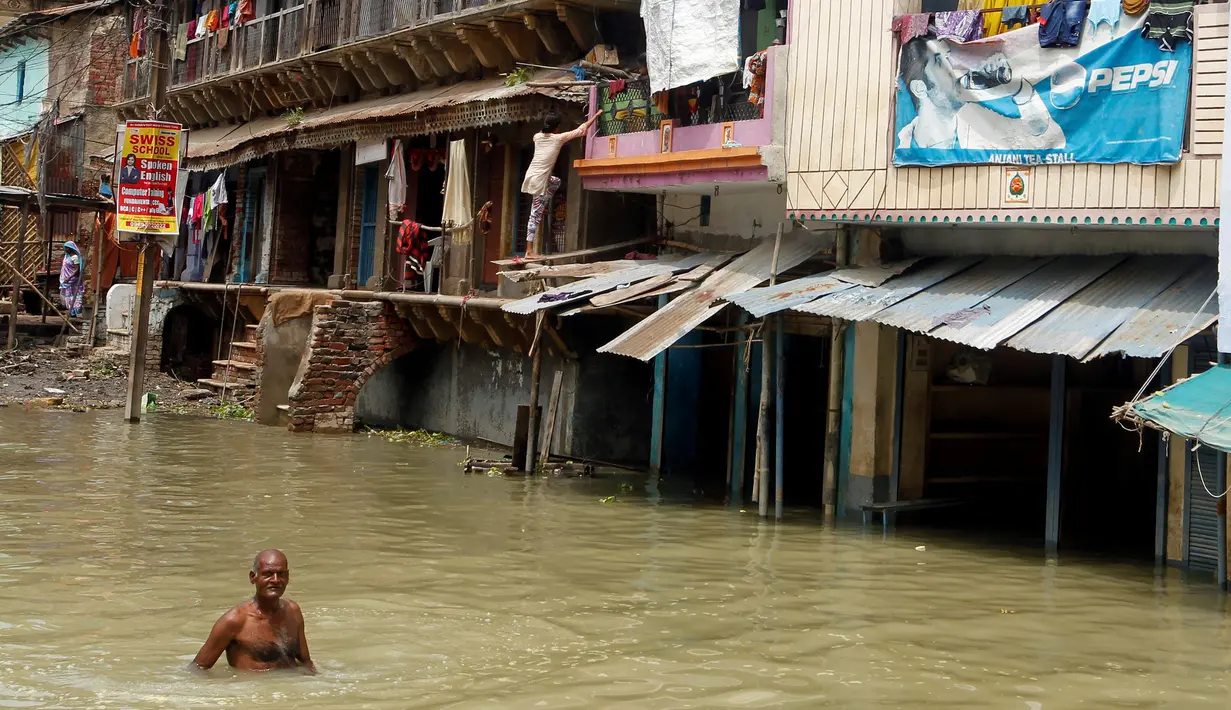Warga melintasi banjir yang menggenangi kawasan Allahabad, India (26/8). Sekitar 300 orang dikabarkan tewas dalam peristiwa banjir bandang tersebut. (REUTERS/Jitendra Prakash)