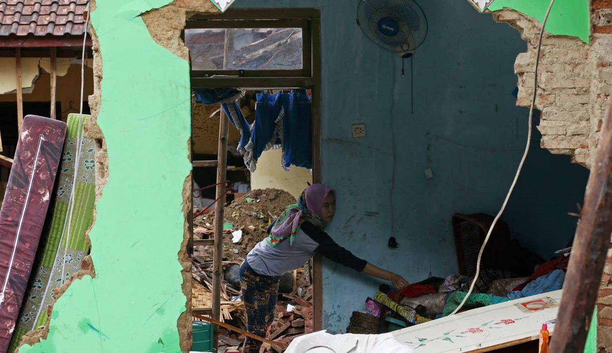 Seorang wanita membersihkan puing-puing dari rumahnya di desa Carita, Indonesia yang dilanda tsunami, Banten, Kamis, (27/12). Pemerintah telah memperluas zona larangan di sekitar pulau gunung berapi pulau yang memicu tsunami. (AP Photo/Achmad Ibrahim)