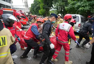 Petugas terus melakukan penyisiran ke seluruh bagian gedung hingga lantai enam. Tampak dalam foto, personel dari Dinas Penanggulangan Kebakaran dan Penyelamatan dibantu tim dari Brimob Polri mengevakuasi jenazah korban kebakaran di Jakarta, Selasa 9 Desember 2025. (AP Photo/Dita Alangkara)