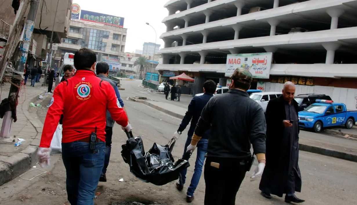 Petugas medis membawa mayat korban ledakan bom di sebuah pasar di Baghdad, Irak (31/12). Diketahui dua bom meledak, dan salah satunya diyakini sebagai bom bunuh diri. (Reuters/Ali al-Mashhadan 