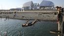 Wisatawan berlibur sambil berenang pada Laut Hitam dekat Fisht Olympic Stadium di Sochi, Rusia, (17/5/2018). Stadion tersebut akan menjadi saksi laga perdana Portugal melawan Spanyol. (AP/Andre Penner)