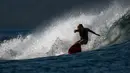 Seorang peselancar menaiki ombak di Pantai Lhoknga, Kabupaten Aceh Besar, Provinsi Aceh, Indonesia, 20 Februari 2023. Dengan tiga level ombak yang berbeda, Pantai Lhoknga sangat cocok bagi para penggemar olahraga pemacu adrenalin seperti selancar. (CHAIDEER MAHYUDDIN/AFP)