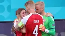 Segera setelah mengetahui bahwa Christian Eriksen kolaps, Simon Kjaer dan Kasper Schmeichel pun langsung menghampiri istri dari rekannya tersebut dan berusaha menenangkannya. (Foto: AFP/Pool/Wolfgang Rattay)