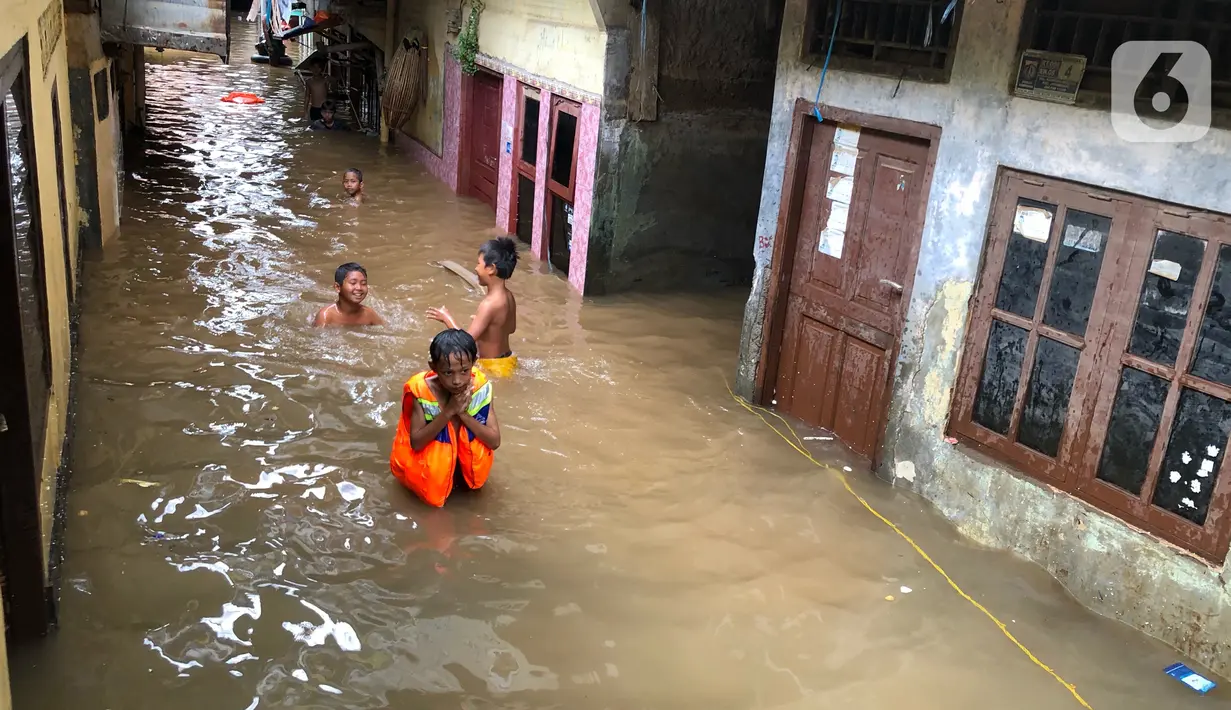 Anak-anak bermain di tengah banjir yang merendam kawasan Kebon Pala, Jakarta Timur, Selasa (25/2/2020). Akibat banjir yang tak kunjung surut, aktivitas warga di kawasan tersebut menjadi terganggu, terlebih dengan adanya pemadaman listrik. (Liputan6.com/Immanuel Antonius)