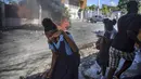 Pelajar berlari melewati barikade yang dibakar pengunjuk rasa saat protes menuntut pembebasan orang-orang yang diculik di Port-au-Prince, Haiti, 25 November 2021. Haiti mengalami peningkatan kasus penculikan terkait geng dan banyak yang menuntut uang tebusan. (AP Photo/Odelyn Joseph)