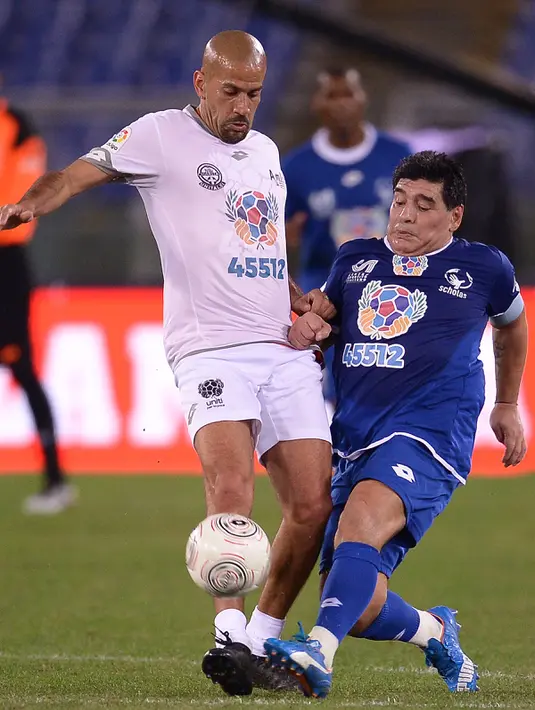 Marodana berusaha melewati mantan pemain MU, Juan Sebastian Veron pada  pertandingan amal 'United for Peace' di stadion Olimpyco, Roma, Italia (12/10). Lebih dari 20.000 penonton menyaksikan pertandingan tersebut. (AFP Photo/Filippo Monteforte)