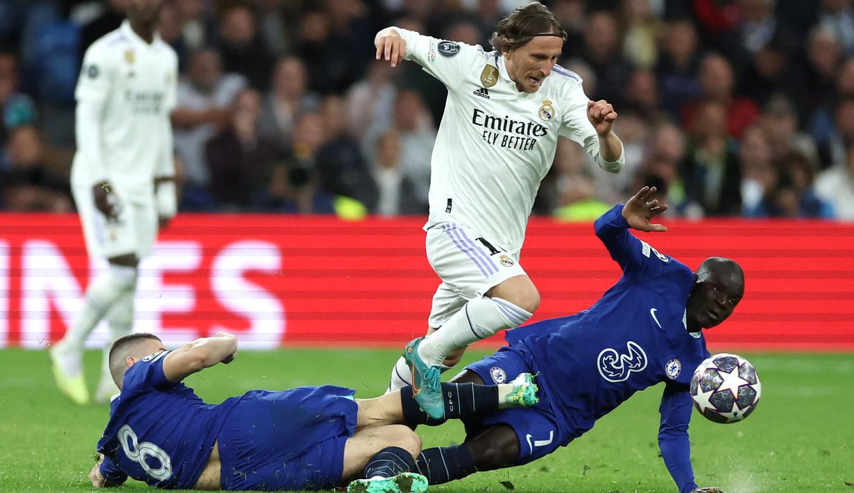 Pemain Real Madrid, Luka Modric berusaha melewati pemain Chelsea, Mateo Kovacic (kiri) dan N'Golo Kante pada laga leg pertama Liga Champions 2022/2023 di Santiago Bernabeu, Madrid, Kamis (13/04/2023) WIB. Los Blancos menang dengan skor 2-0. (AFP/Pierre-Philippe Marcou)