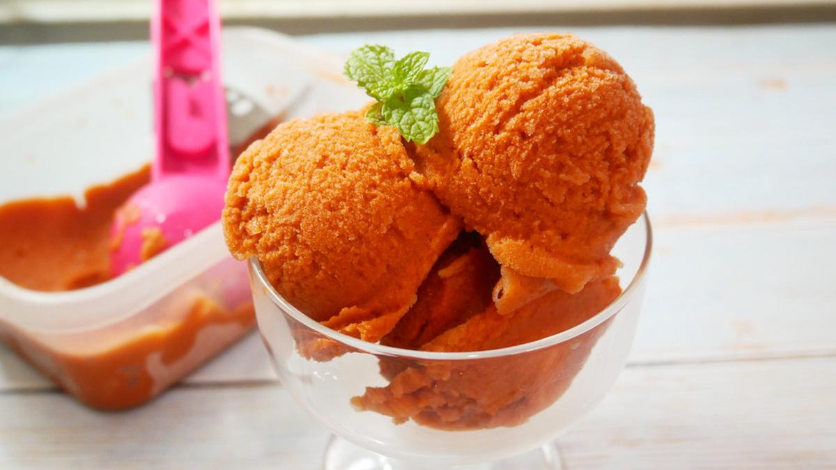Es Krim Thai Tea Lembut: Es krim berwarna jingga cerah dengan tekstur lembut dan rasa khas Thai Tea