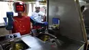 Seorang koki memperhatikan robot yang sedang membuat masakan di restoran robot di Hefei, China, Jumat (26/12/2014). (REUTERS/Stringer)