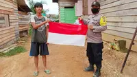 Suku Talang Mamak menerima bendera merah putih yang diberikan personel Polres Indragiri Hulu. (Liputan6.com/M Syukur)