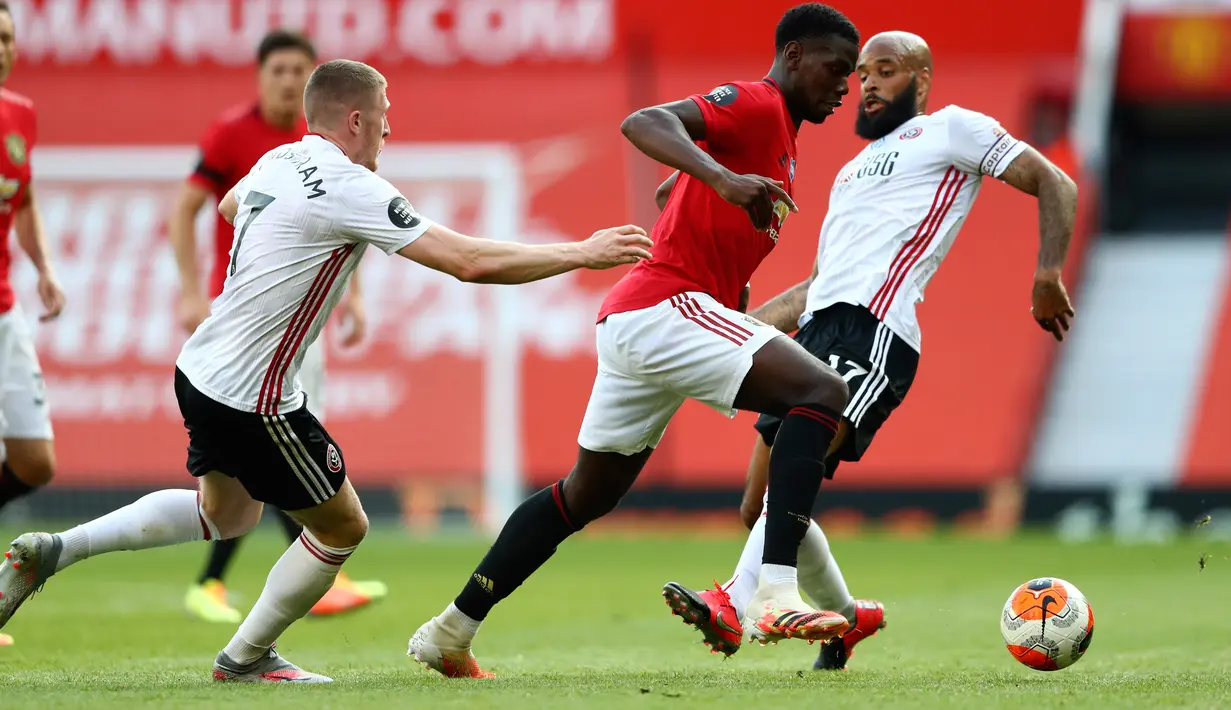 Gelandang Manchester United, Paul Pogba (tengah) berusaha mengontrol bola dari kawalan pemain Sheffield United John Lundstram dan David McGoldrick pada pertandingan lanjutan Liga Inggris di Old Trafford, Inggris (24/6/2020). MU menang telak 3-0 atas Sheffield United. (Michael Steele/Pool via AP)