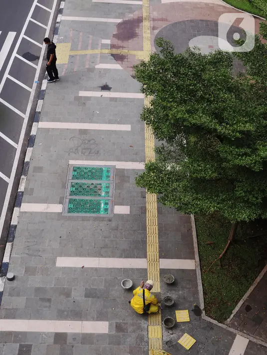 Perbaikan garis kuning oleh petugas Dinas Bina Marga di trotoar kawasan Tanah Abang, Jakarta, Sabtu (22/5/2021). Garis kuning di trotoar yang dibuat khusus untuk jalur penyandang tunanetra tersebut diperbaiki agar nantinya dapat dilintasi dengan aman dan nyaman. (Liputan6.com/Angga Yuniar)