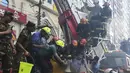 Petugas pemadam kebakaran Bangladesh menyelamatkan seorang pria dari gedung kantor yang terbakar di Dhaka (28/3). Kebakaran besar melanda gedung perkantoran yang menewaskan sedikitnya lima orang dan lainnya masih terperangkap dalam gedung yang terbakar tersebut. (AFP/Munir Uzzaman)