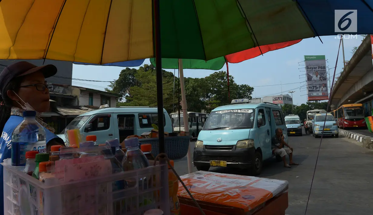 Pedagang kaki lima menjajakan dagangannya di depan angkot yang menunggu penumpang di Terminal Kampung Melayu, Jakarta timur, Jumat (2/8/2019). Rancangan pembatasan usia kendaraan di atas 10 tahun tersebut dibuat untuk menghindari angkutan umum yang kondisi tak laik jalan. (merdeka.com/Imam Buhori)