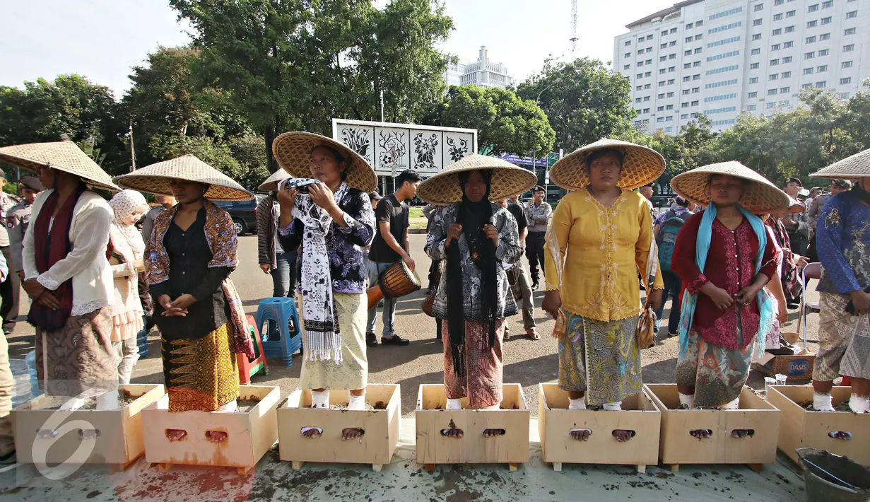 Sejumlah perempuan asal Pegunungan Kendeng, Jawa Tengah melakukan aksi semen kaki di depan Istana Negara, Jakarta, Selasa (12/4). Aksi tersebut merupakan bentuk protes atas pembangunan pabrik semen di wilayah mereka. (Liputan6.com/Immanuel Antonius) 