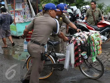 Petugas Satpol PP membawa barang dagangan milik pedagang kopi keliling saat melakukan razia di kawasan SCBD, Jakarta, Senin (21/11). Satpol PP merazia dan menyita dagangan yang beroperasi di kawasan tersebut. (Liputan6.com/Gempur M Surya)