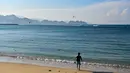 Tidak hanya itu, pasir putih Pantai Lhoknga yang lembut mengundang pengunjung untuk berjalan-jalan telanjang kaki di tepi pantai sambil menikmati hangatnya sinar matahari. Tampak dalam foto, sekumpulan capung terlihat saat seorang peselancar menuju ke air untuk menangkap ombak di pantai Lhoknga, provinsi Aceh, pada Senin 12 Januari 2026. (CHAIDEER MAHYUDDIN/AFP)