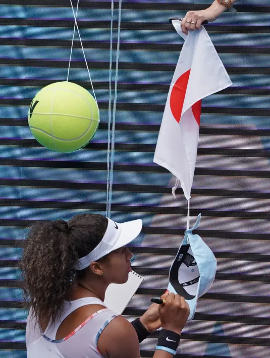Petenis Jepang Naomi Osaka menandatangani topi yang disodorkan penonton usai mengalahkan petenis Republik Ceko Marie Bouzkova pada Australia Terbuka di Melbourne, Australia, Senin (20/1/2020). Penonton menyodorkan topi, bendera, hingga bola untuk ditandatangani Naomi. (AP Photo/Lee Jin-man)