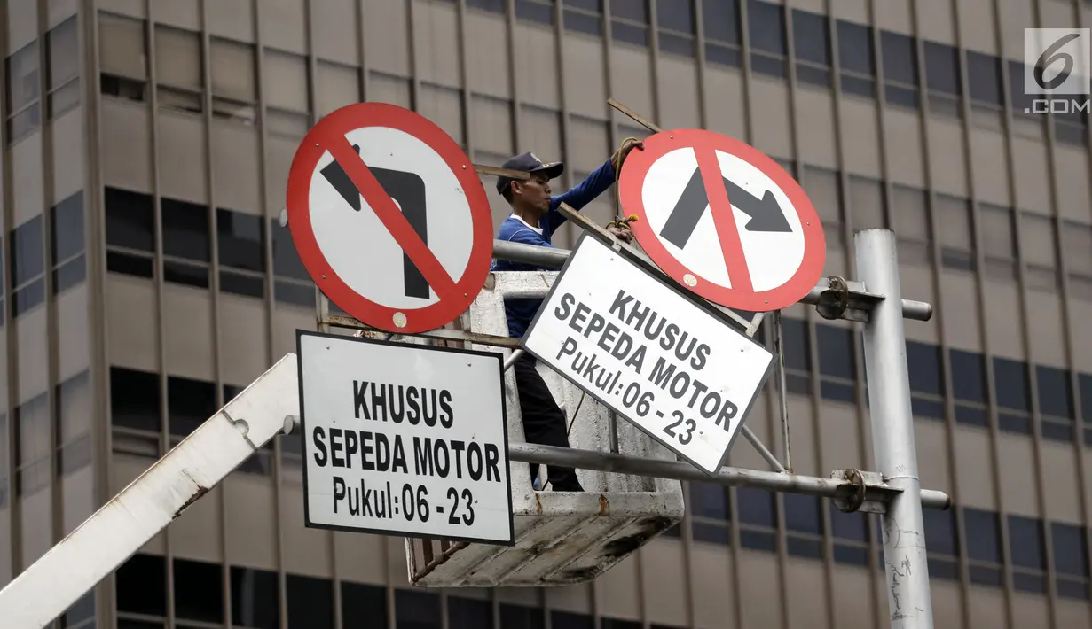 Petugas Dishub mencabut rambu larangan melintas untuk sepeda motor di Jalan MH Thamrin, Jakarta Pusat, Rabu (10/1). MA membatalkan Pergub DKI soal pelarangan sepeda motor melintasi Jalan MH Thamrin hingga Medan Merdeka Barat. (Liputan6.com/Arya Manggala)