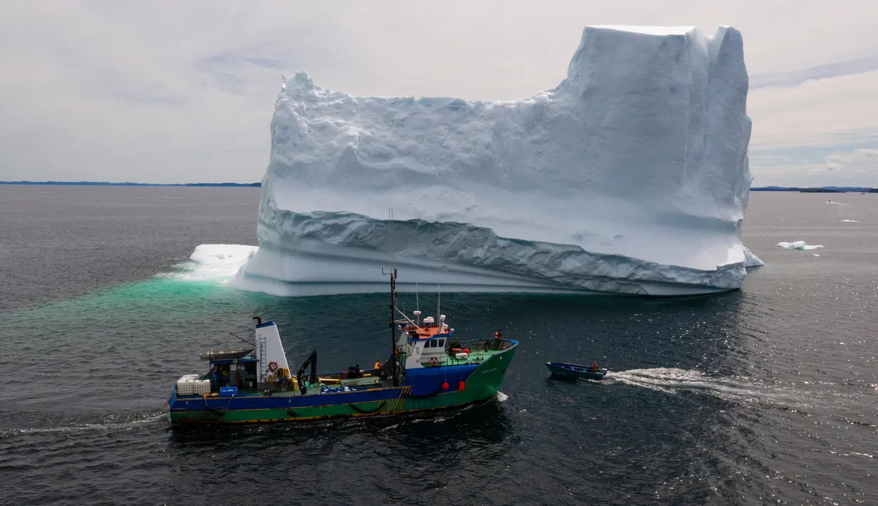 Kapal Kapten Edward Kean melewati gunung es terapung di Teluk Bonavista, Newfoundland, Kanada, 29 Juni 2019. Pada tahun 2018, lebih dari 500.000 wisatawan mengunjungi Provinsi Newfoundland untuk menyaksikan gunung es terapung. (Johannes Eisele/AFP)