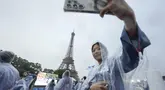 Asom Kim, fisioterapis dari tim Korea Selatan berfoto selfie dengan latar belakang Menara Eiffel dari atas kapal menyusuri Sungai Seine saat upacara pembukaan Olimpiade Paris 2024, Jumat (26/7/2024). (AP Photo/Lee Jin-man, Pool)