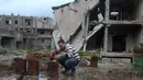 Mohamed Ataya menyiram tanaman yang ditanam di atap bangunan yang rusak di wilayah Ghouta timur di ibukota Damaskus, Suriah (3/3). Akibat perang, kini Abu Maher menjadi pembudidaya bibit tanaman demi bertahan hidup. (AFP/Amer Almohibany)