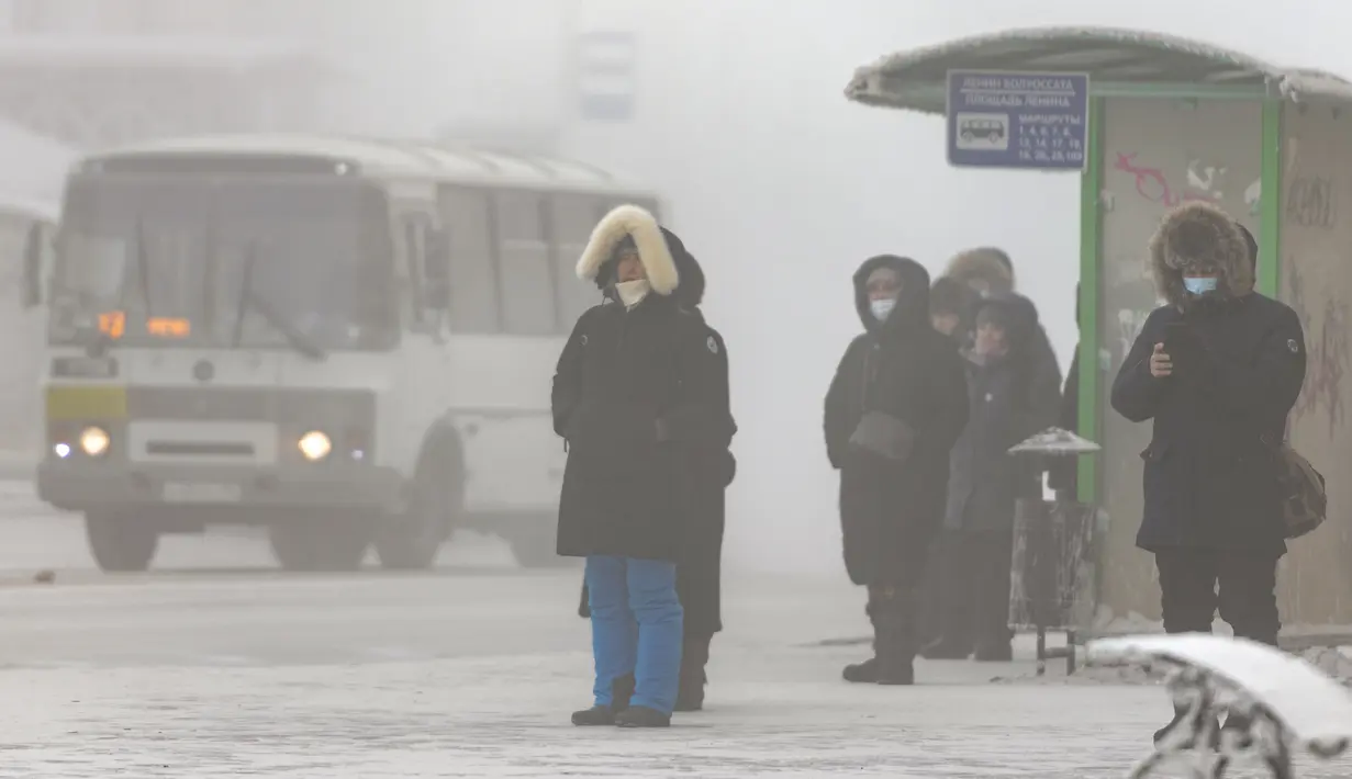 Orang-orang, kebanyakan dari mereka mengenakan masker, berdiri di halte bus saat suhu turun hingga sekitar -50 derajat (-58 derajat Fahrenheit) di Yakutsk, Rusia pada Rusia, Sabtu (16/1/2021).  Yakutsk atau Yakutia tersohor sebagai kota terdingin di dunia. (AP Photo/Tatiana Gasich)