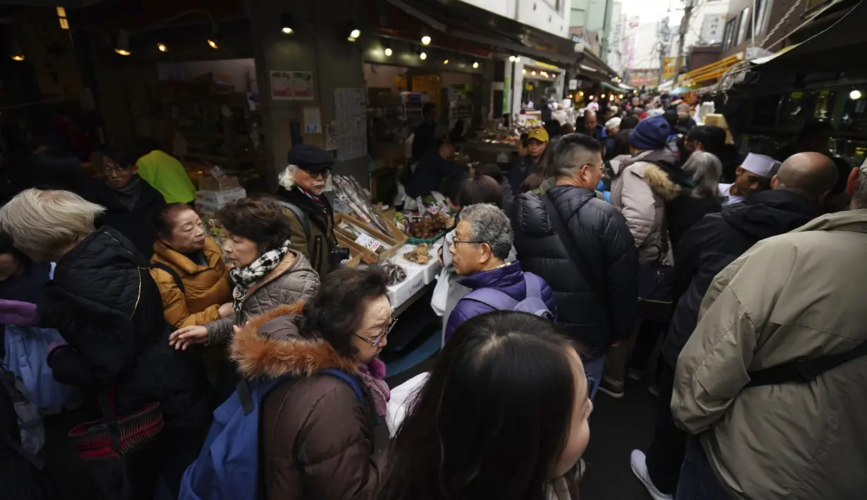 Wisatawan dan warga yang sedang mencari bahan-bahan untuk membuat makanan tahun baru atau osechi memenuhi jalanan Pasar Tsukiji, Tokyo, Jepang, Kamis (26/12/2019). Sebagian besar makanan osechi dimasak sangat manis, asin, atau diacar dengan cuka. (AP Photo/Eugene Hoshiko)