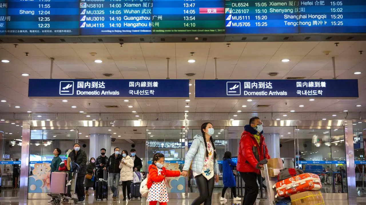 Penerbangan dari Wuhan Ditutup: Pelancong berjalan melintasi papan informasi tentang penerbangan dari Wuhan telah dibatalkan di Bandara Internasional Ibu Kota Beijing pada Kamis (23/1/2020).