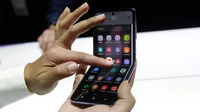 Seorang pekerja Samsung mendemonstrasi Galaxy Z Flip pada acara Unpacked 2020 di San Francisco, Selasa (11/2/2020). Menjadi perangkat kedua dengan layar lipat karyanya, Samsung menghadirkan perbedaan desain pada Galaxy Z Flip jika dibandingkan ponsel generasi pertama, Galaxy Fold. (AP/Jeff Chiu)