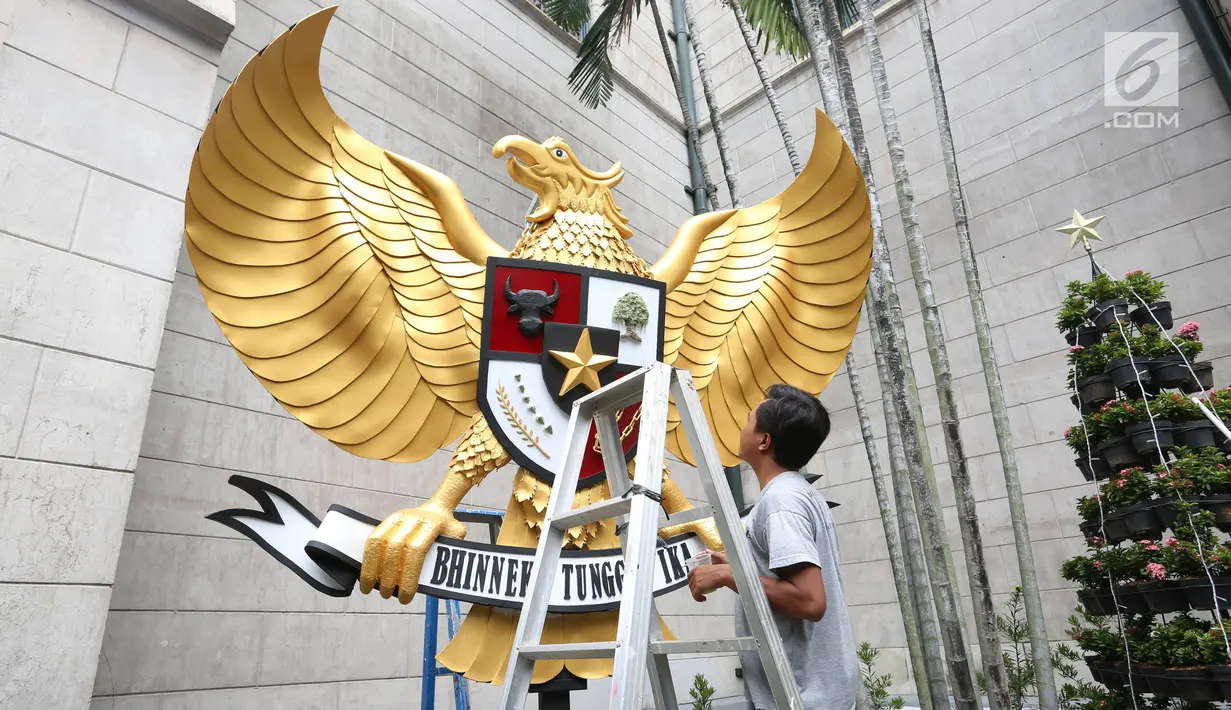 Seorang pria memasang patung Garuda Pancasila di halaman luar Gereja Katedral, Jakarta, Sabtu (23/12). Berbagai dekorasi seperti pohon natal, aksesoris serta tidak ketinggalan patung Garuda Pancasila ditata sedemikian rupa. (Liputan6.com/Angga Yuniar)