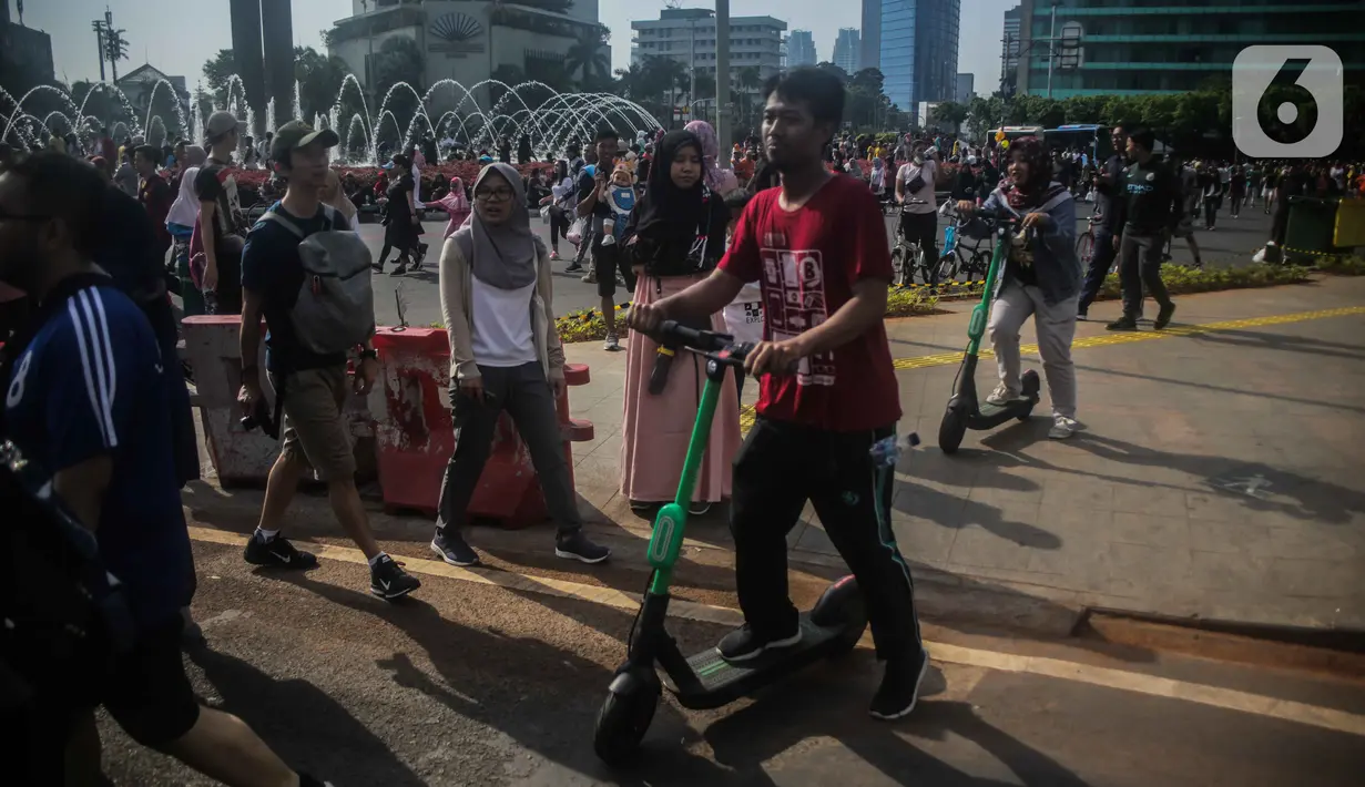 Warga mengendarai skuter listrik saat Car Free Day (CFD) di kawasan Bundaran HI, Jakarta, Minggu (17/11/2019). Skuter listrik dilarang digunakan saat CFD karena dianggap masih menggunakan motor sehingga tak bisa disesuaikan dengan sepeda. (Liputan6.com/Faizal Fanani)