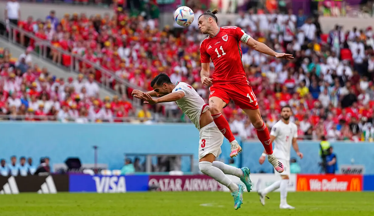 Pemain Wales Gareth Bale (kanan) melompat untuk merebut bola dengan pemain Iran Ehsan Hajsafi pada pertandingan sepak bola Grup B Piala Dunia 2022 di Stadion Ahmad Bin Ali, Al Rayyan, Qatar, Jumat (25/11/2022). Iran mengalahkan Wales dengan skor 2-0. (AP Photo/Pavel Golovkin)