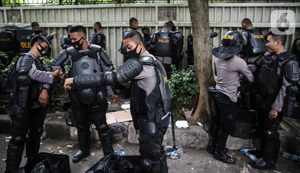 Personel Brimob bersiap mengenakan perlengkapan pelindung diri di Kawasan Bundaran HI, Jakarta, Selasa (13/10/2020). Sebanyak kurang lebih 12 ribu personel gabungan TNI, Polri dan Pemprov DKI Jakarta diterjunkan mengawal aksi tolak Undang-Undang Cipta Kerja Omnibus Law. (Liputan6.com/Faizal Fanani)