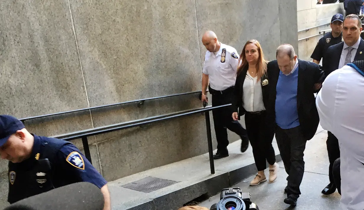 Produser Hollywood Harvey Weinstein dibawa ke pengadilan pidana New York, Jumat (25/5). Selain membayar uang jaminan, Weinstein juga menyerahkan paspor serta bersedia mengenakan alat pelacak (GPS) sehingga bisa dimonitor keberadaannya. (AP/Richard Drew)