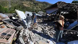Orang-orang membersihkan puing-puing dari bangunan rumah yang rusak di Menggala, Lombok Utara, Rabu (8/8). Laporan terakhir mengatakan, gempa Lombok telah memakan 105 korban jiwa, dan lebih 70.000 orang kehilangan tempat tinggal. (AFP/ADEK BERRY)