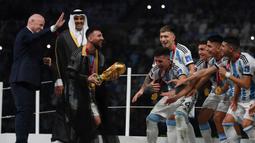 Setelah pemberian trofi Piala Dunia oleh Presiden FIFA, Lonel Messi lalu menghampiri rekan-rekannya yang sudah menantikan trofi tersebut di atas panggung. (AFP/Franck Fife)