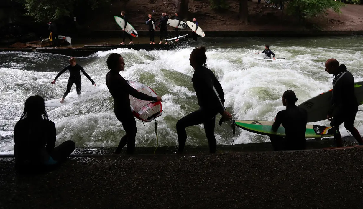 Seorang peselancar bermain ombak buatan di sungai 'Eisbach' di taman English Garden di Munich, Jerman, Kamis (16/7/2020). (AP Photo/Matthias Schrader)