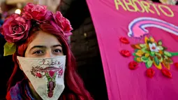 Seorang wanita menutupi wajahnya dengan saputangan saat aksi mendukung undang-undang untuk melegalkan aborsi di Santiago, Chile (25/7). Mereka menuntut untuk melegalkan aborsi dalam tiga situasi. (AP Photo/Esteban Felix)