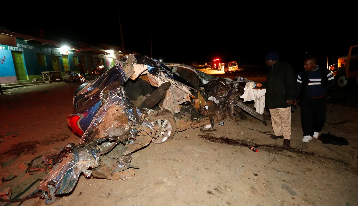 Sejumlah warga melihat bangkai mobil usai terjadi kecelakaan di Kenya, Minggu (11/12). Mobil tangki pembawa gas kimia hilang kendali dan menabrak sejumlah mobil yang menyebabkan 30 orang tewas. (REUTERS / Stringer)