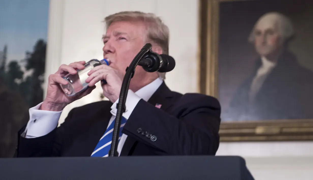 Presiden Amerika Serikat (AS), Donald Trump meminum air dari botol mineral disela menyampaikan pidatonya di Ruang Diplomatik, Gedung Putih, Rabu (15/11). Video Trump minum tersebut menuai komentar dari warganet di media sosial. (NICHOLAS KAMM/AFP)