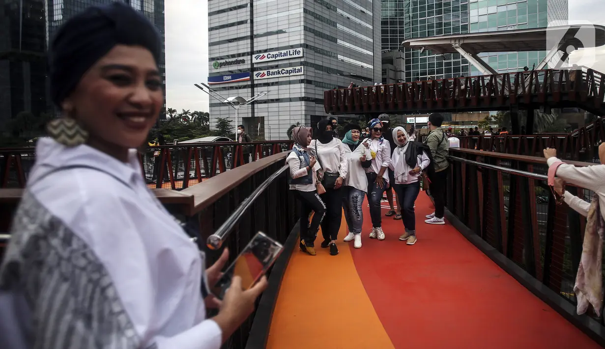 Warga berpose saat difoto di Jembatan Penyeberangan Orang (JPO) Pinisi, Jalan Jenderal Sudirman, Karet, Jakarta, Selasa (15/3/2022). Belum lama ini, Pemprov DKI Jakarta meresmikan JPO berbentuk spesial tersebut yang membentang di atas Jalan Jenderal Sudirman. (Liputan6.com/Johan Tallo)
