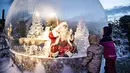 Seseorang yang berpakaian seperti Sinterklas terlihat dalam bola salju seukuran aslinya saat membuka musim Natal di Kebun Binatang Aalborg, di tengah krisis virus corona yang berlanjut, di Aalborg, Denmark pada Jumat (13/11/2020). (Henning Bagger / Ritzau Scanpix / AFP)
