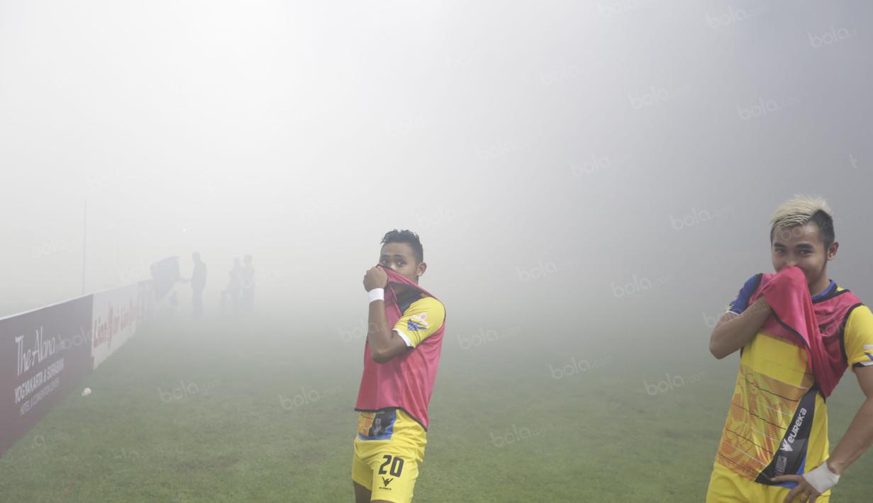 Pemain Persiba Balikpapan  menutup hidung  saat melakukan pemanasan akibat asap flare pada lagaTorabika SC 2016 di Stadion Gelora Bangkalan, Senin(13/6/2016).  (Bola.com/Nicklas Hanoatubun)