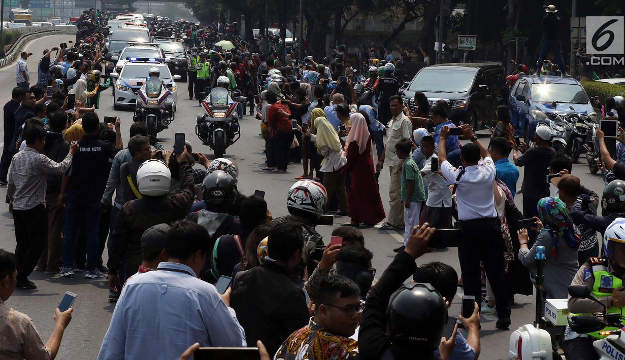 Iring-iringan mobil jenazah yang membawa almarhum Presiden ke-3 RI, BJ Habibie melintasi Jalan Gatot Subroto menuju TMP Kalibata, Jakarta, Kamis (12/9/2019). Warga secara khusus meluangkan waktu menyambut jenazah BJ Habibie untuk memberikan penghormatan terakhir. (Liputan6.com/Johan Tallo)