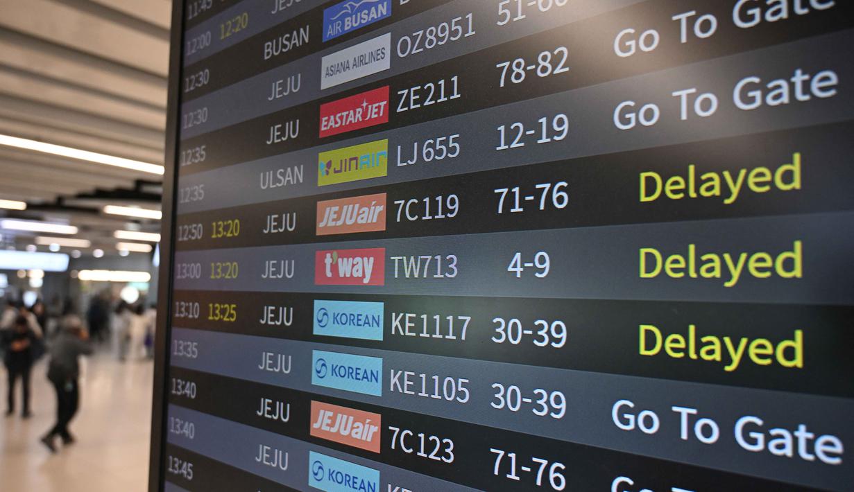 Sementara, untuk kantor-kantor, termasuk pemerintahan hingga perbankan, pemerintah Korea Selatan meminta para pekerja untuk mulai bekerja satu jam lebih lambat. Tampak dalam foto, penumpang berjalan melewati papan informasi yang menampilkan penerbangan tertunda di Bandara Gimpo, Seoul, pada Kamis 13 November 2025, pada hari ujian masuk perguruan tinggi tahunan yang dikenal secara lokal sebagai Suneung. (Jung Yeon-je/AFP)