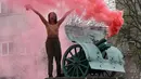 Seorang aktivis wanita gerakan hak perempuan Femen meneriakkan slogan-slogan di tiang monumen Soviet di pusat kota Kiev, Ukraina (7/11). Aktivis tersebut menggelar aksi memperingati 100 tahun Revolusi Bolshevik. (AFP Photo/Genya Savilov)