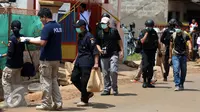 Penyidik dari kepolisian membawa keluar sejumlah barang usai melakukan olah tempat kejadian perkara di rumah terduga anggota jaringan teroris, Bekasi, Minggu (11/12). (Liputan6.com/Johan Tallo)